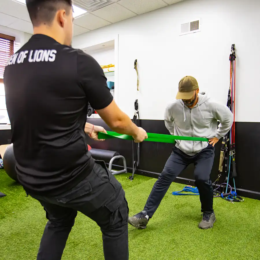 Therapist coaching resistance band training on the turf at our Newark clinic